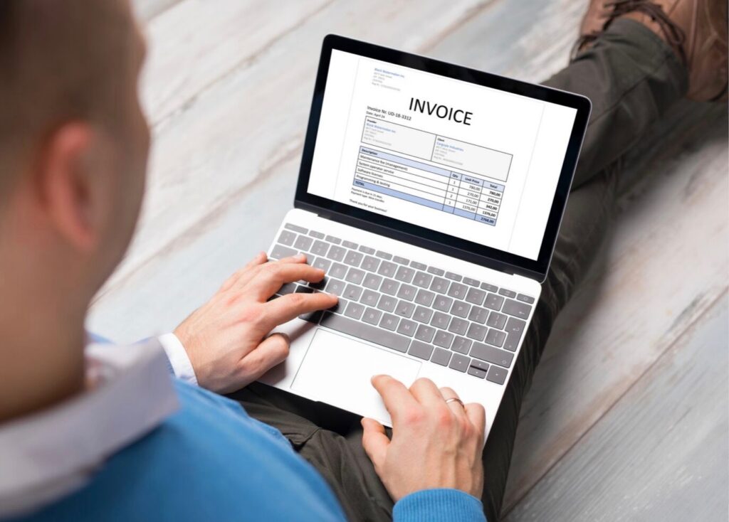 man sitting with laptop looking at invoice